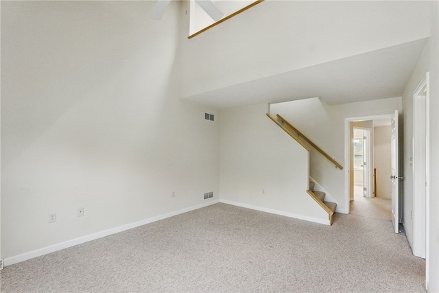 unfurnished living room with light colored carpet, stairway, and baseboards