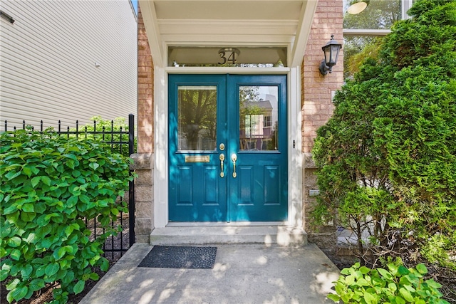 entrance to property featuring french doors, fence, and brick siding