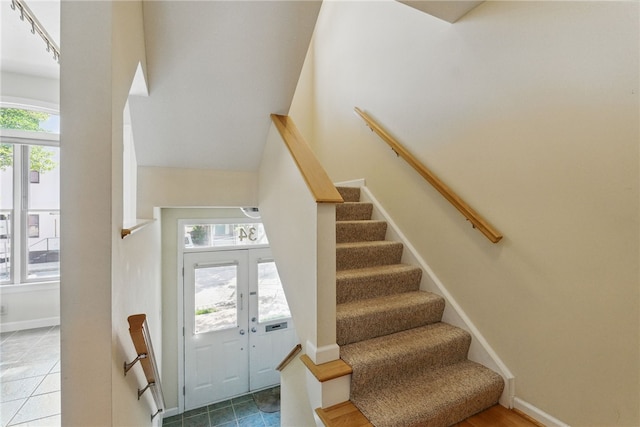 tiled entryway with plenty of natural light, stairs, french doors, and baseboards