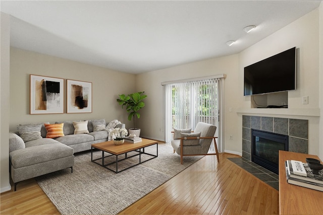 living area featuring hardwood / wood-style floors, a tile fireplace, and baseboards