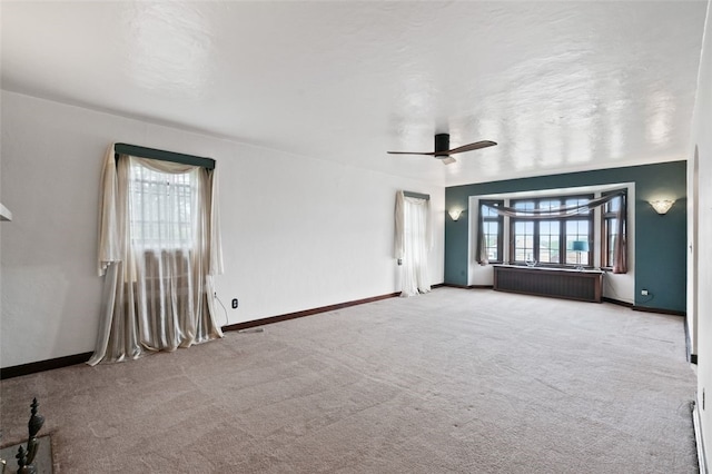 empty room featuring radiator, plenty of natural light, and carpet