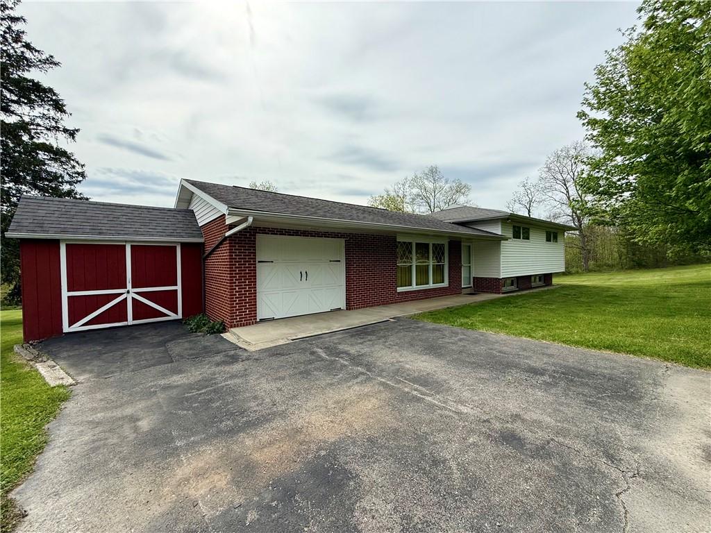 view of front of house with a garage, a front yard, brick siding, asphalt driveway, and an outbuilding