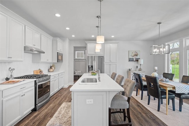 kitchen featuring stainless steel appliances, a sink, under cabinet range hood, a chandelier, and recessed lighting