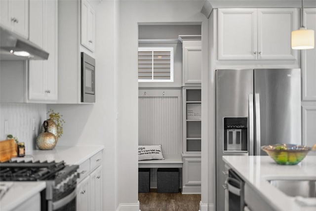 kitchen with light countertops, appliances with stainless steel finishes, dark wood finished floors, white cabinetry, and under cabinet range hood