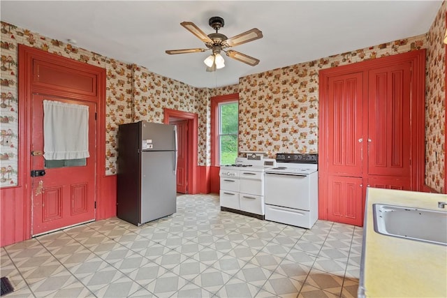 kitchen featuring freestanding refrigerator, white electric range oven, a ceiling fan, light flooring, and a sink