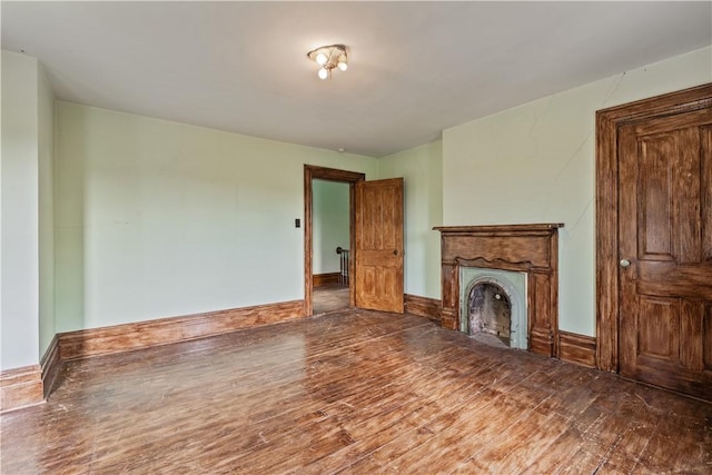 unfurnished living room with wood finished floors, a fireplace, and baseboards