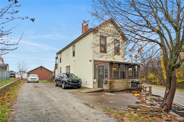 4974 Williamsport Rd, Elizabeth Twp/Boro, PA 15037 - view of side of home with a chimney, gravel driveway, brick siding, and a sunroom