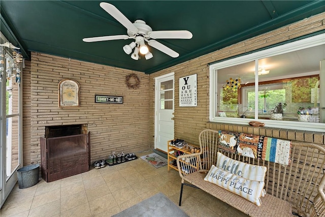 sunroom / solarium with a ceiling fan and a fireplace