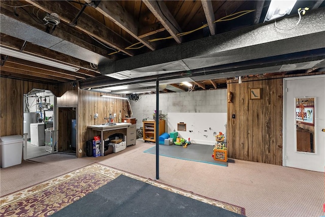 basement with wooden walls, carpet, water heater, and washer / clothes dryer