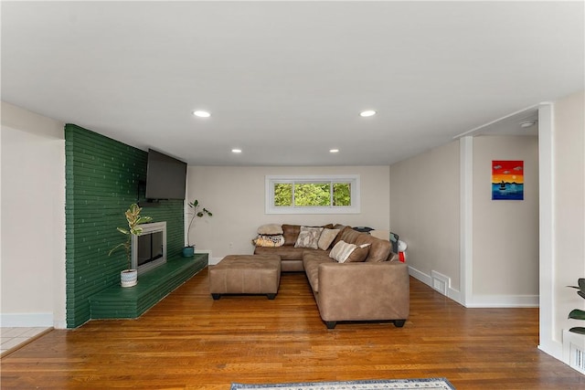 living area with wood finished floors, baseboards, recessed lighting, and a fireplace
