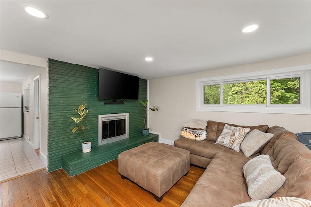 living area with baseboards, wood finished floors, recessed lighting, and a fireplace