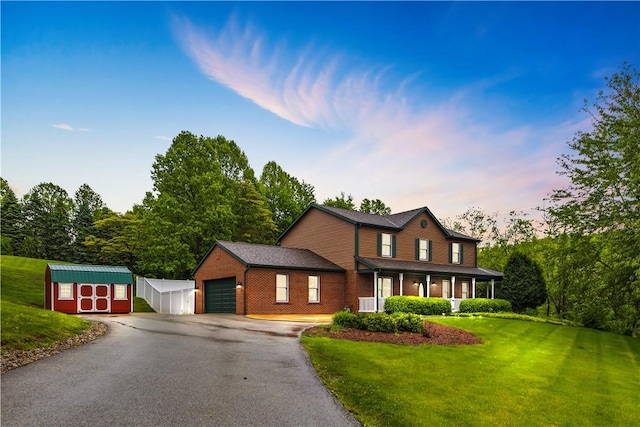 view of front of property with a storage unit, asphalt driveway, a front lawn, an outdoor structure, and brick siding