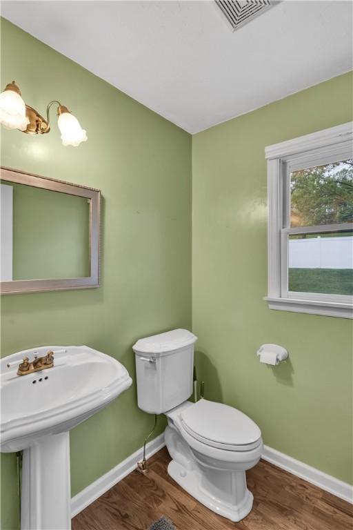 half bath featuring baseboards, wood finished floors, toilet, and a sink