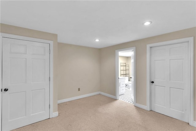 unfurnished bedroom featuring light carpet, baseboards, recessed lighting, and ensuite bathroom