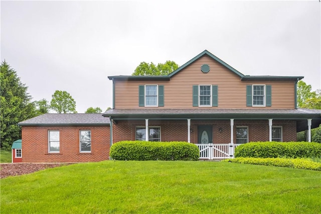 view of front of house with a front yard, a porch, and brick siding