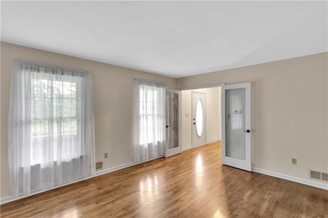 spare room featuring plenty of natural light, wood finished floors, and baseboards