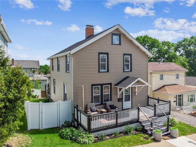 rear view of house featuring a chimney, a wooden deck, and a gate