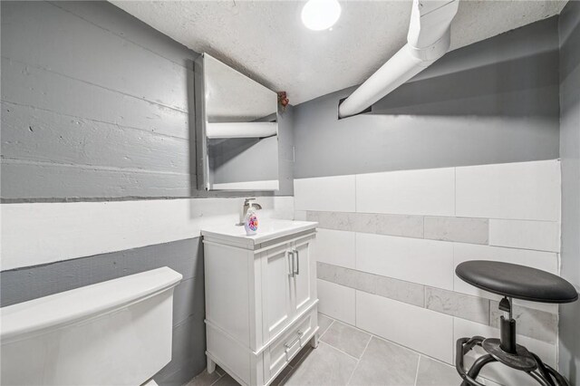 bathroom with toilet, vanity, and tile patterned flooring