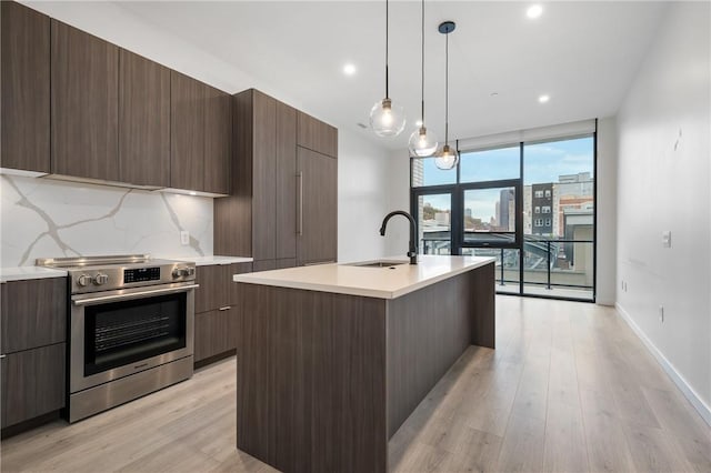 kitchen featuring stainless steel electric stove, modern cabinets, a sink, light wood-type flooring, and floor to ceiling windows