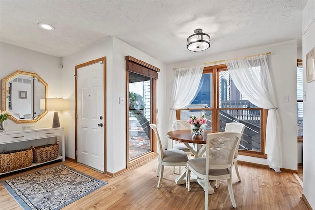 dining room with a textured ceiling, light wood-style flooring, baseboards, and recessed lighting