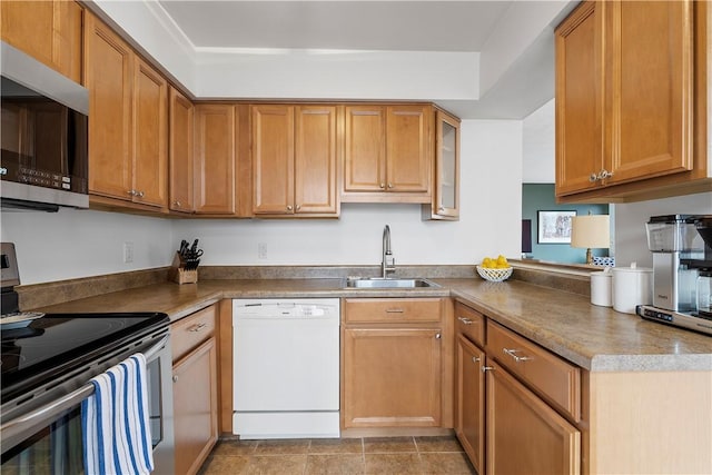 kitchen featuring stainless steel appliances, a sink, brown cabinets, a peninsula, and glass insert cabinets