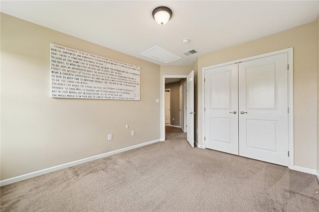 unfurnished bedroom with carpet floors, baseboards, attic access, and a closet
