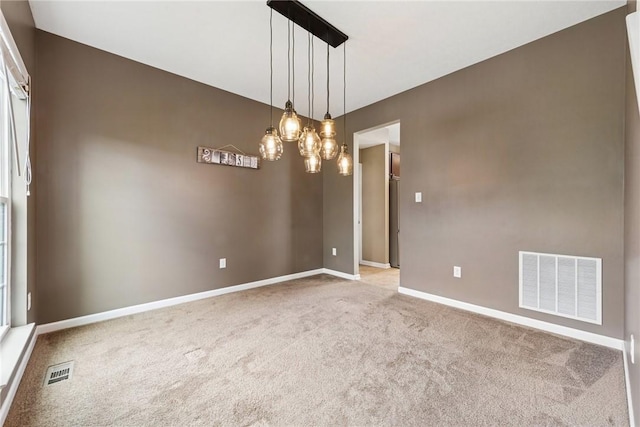 carpeted empty room with baseboards and a chandelier