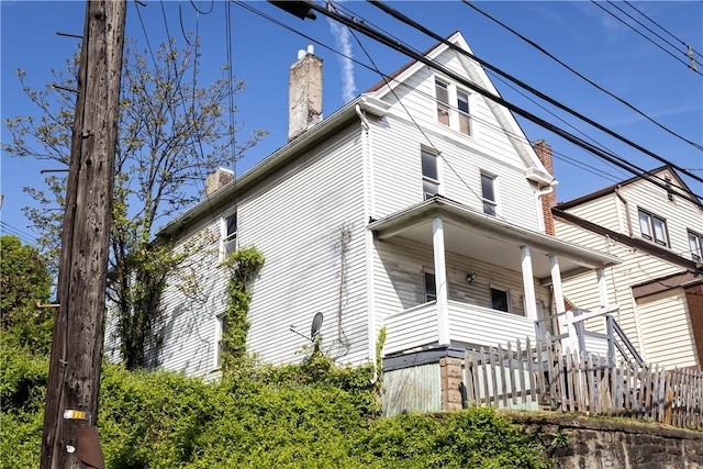 view of home's exterior with a chimney and a porch