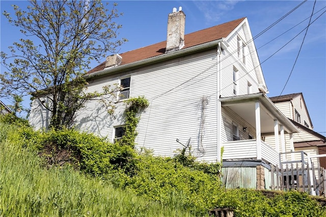 view of side of home featuring a chimney and a balcony