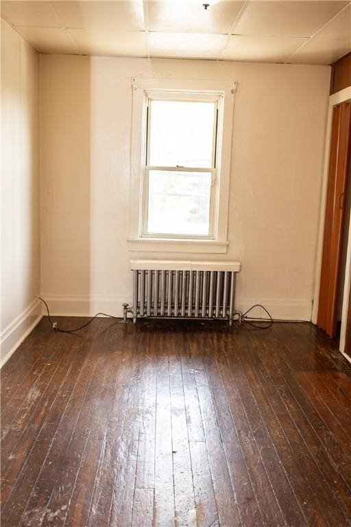 spare room featuring radiator, hardwood / wood-style floors, and baseboards