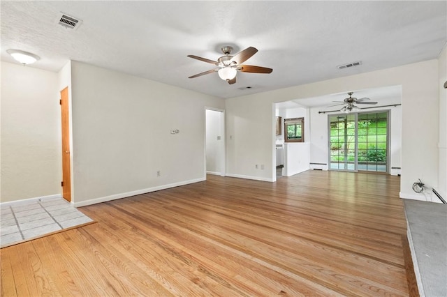 empty room with a ceiling fan, baseboard heating, and light wood-style flooring