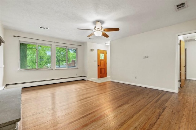 unfurnished living room with a baseboard radiator, attic access, ceiling fan, wood finished floors, and baseboards