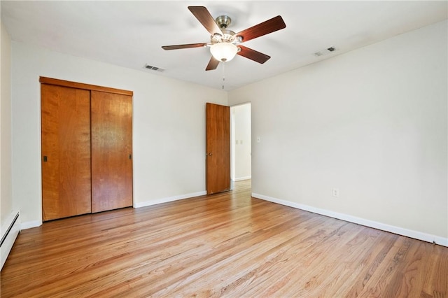 unfurnished bedroom with light wood-style floors, a closet, baseboards, a ceiling fan, and a baseboard heating unit