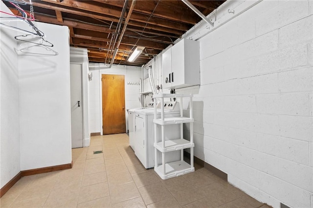unfinished basement featuring washing machine and clothes dryer, light tile patterned floors, and baseboards