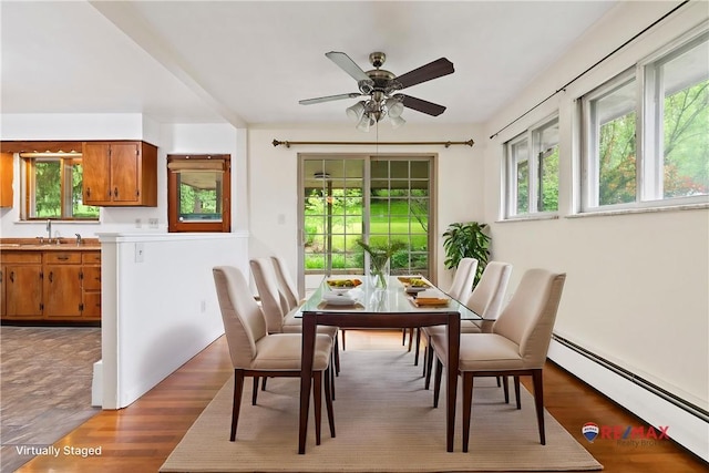 dining room featuring a baseboard radiator, a ceiling fan, and wood finished floors