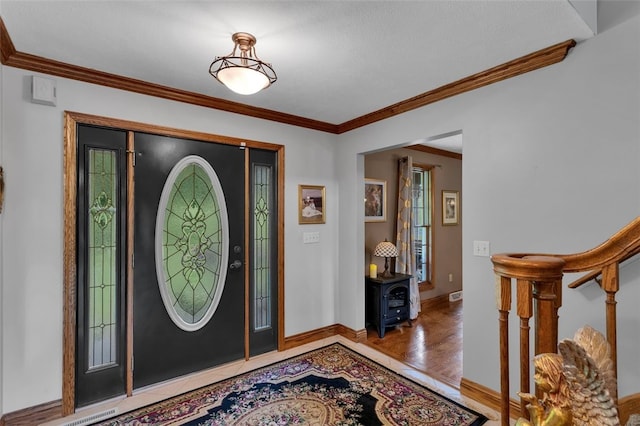 foyer with wood finished floors, crown molding, baseboards, and stairway