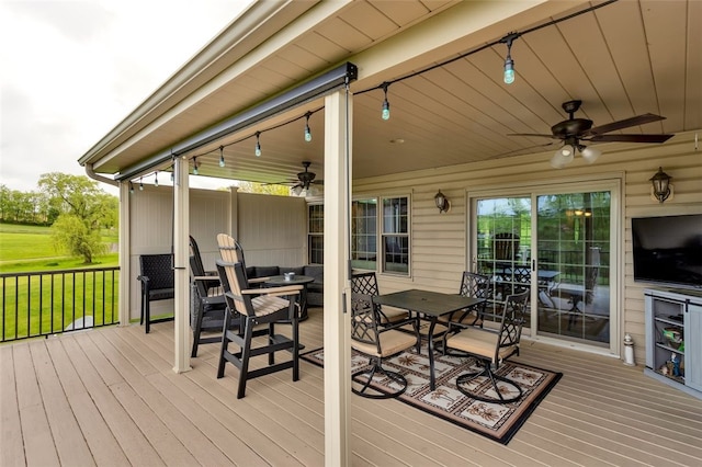 deck with ceiling fan, outdoor dining area, and a lawn