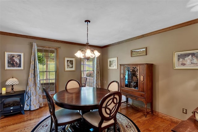 dining room featuring a chandelier, light wood-style floors, a wood stove, and ornamental molding