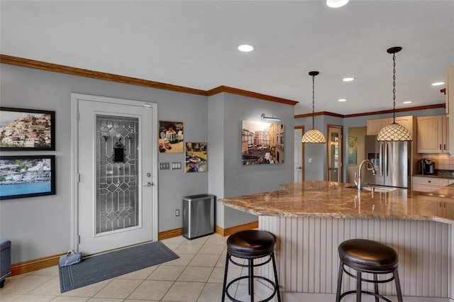 kitchen with stainless steel refrigerator with ice dispenser, baseboards, a sink, recessed lighting, and a kitchen bar