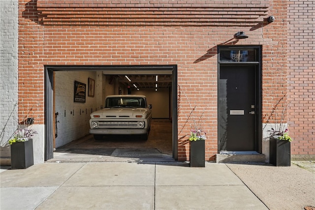 view of exterior entry featuring brick siding, driveway, and a garage