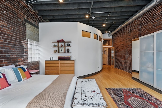 bedroom featuring brick wall and wood finished floors