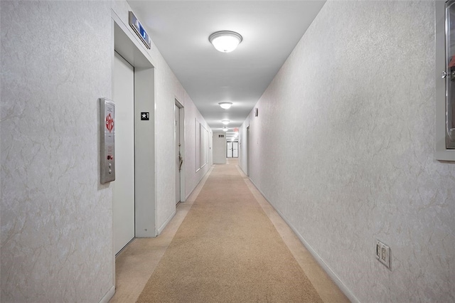 hallway featuring a textured wall and elevator