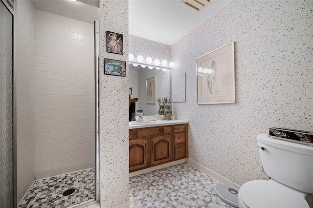 bathroom featuring toilet, a stall shower, vanity, baseboards, and wallpapered walls