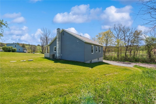 view of side of home featuring a chimney, a yard, and cooling unit