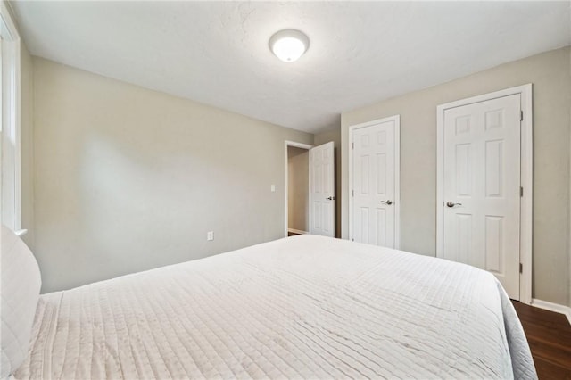 bedroom with dark wood-style floors and baseboards