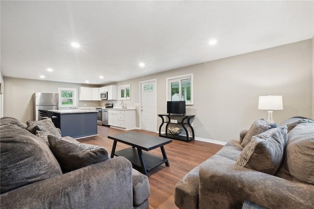 living area featuring recessed lighting, dark wood-style flooring, and baseboards