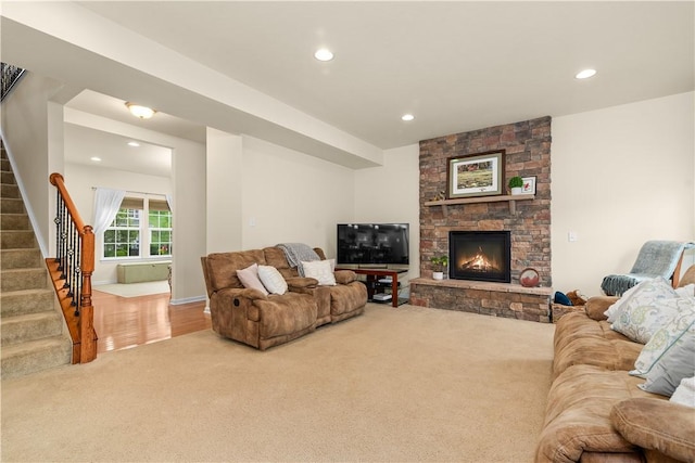 carpeted living room with stairway, recessed lighting, and a stone fireplace