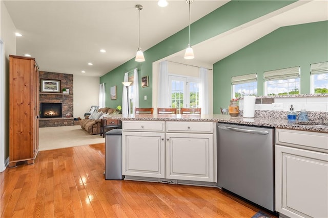 kitchen featuring stainless steel dishwasher, white cabinetry, light wood-style floors, open floor plan, and hanging light fixtures