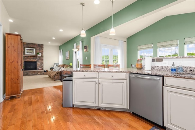 kitchen with stainless steel dishwasher, white cabinetry, light wood-style floors, decorative light fixtures, and open floor plan