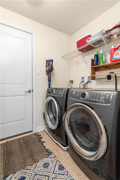 laundry area with washing machine and dryer, tile patterned floors, and baseboards
